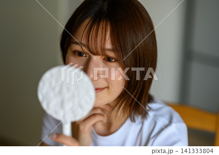 鏡で肌をチェックする女性 141333804