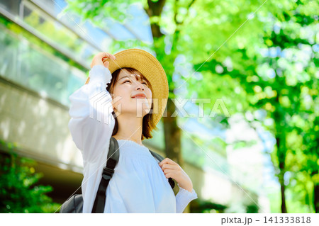 麦わら帽子をかぶった笑顔の女性、新緑と木漏れ日の下で明るい屋外 麦わら帽子をかぶった笑顔の女性、新緑と木漏れ日の下で明るい屋外 141333818