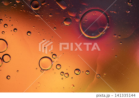 Oil drops creating an abstract pattern with gradients of orange, red, and yellow colors 141335144