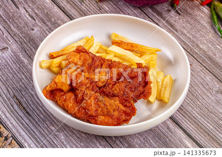 Crispy fried fish fillets with golden french fries on rustic wooden surface Crispy fried fish fillets with golden french fries on rustic wooden surface 141335673