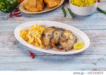 Fried fish steaks with french fries and lemon on white plate Fried fish steaks with french fries and lemon on white plate 141335675