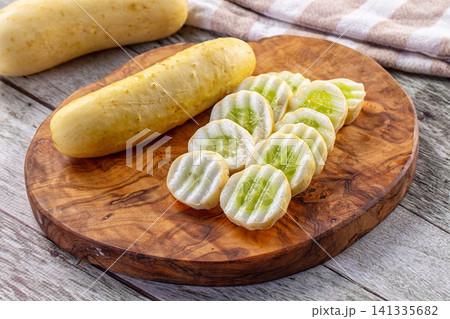 Sliced yellow cucumbers on rustic wooden cutting board with whole cucumbers Sliced yellow cucumbers on rustic wooden cutting board with whole cucumbers 141335682