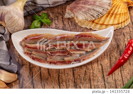 Marinated anchovy fillets with garlic chili basil on rustic wood Marinated anchovy fillets with garlic chili basil on rustic wood 141335728