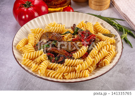 Fusilli pasta with beef liver sun dried tomatoes and pickles on ceramic plate 141335765