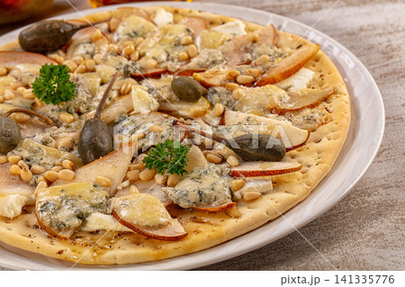 Gourmet flatbread pizza with pear slices, blue cheese, pine nuts, and capers on white plate Gourmet flatbread pizza with pear slices, blue cheese, pine nuts, and capers on white plate 141335776