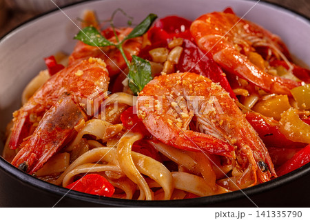 Spicy shrimp udon noodles with red peppers and garlic garnish Spicy shrimp udon noodles with red peppers and garlic garnish 141335790