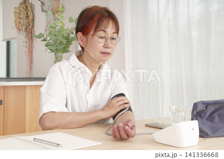 自宅で血圧を測定して記録するシニア女性 141336668