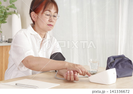 自宅で血圧を測定して記録するシニア女性 自宅で血圧を測定して記録するシニア女性 141336672