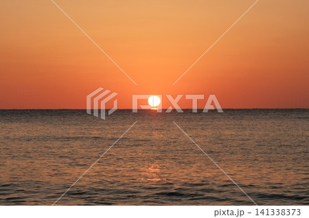 だるまの形が完全に分離して水平線から浮き上がった太陽と海の朝焼け 141338373