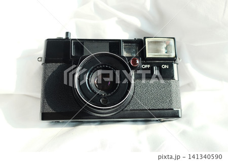Top view of vintage and retro style of black film camera on white bed with natural sunlight Top view of vintage and retro style of black film camera on white bed with natural sunlight 141340590