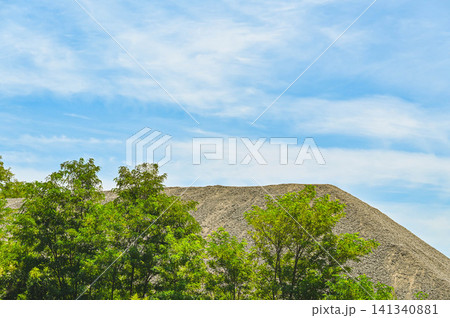 青空と新緑の木々の向こうにそびえる砂利の山 青空と新緑の木々の向こうにそびえる砂利の山 141340881