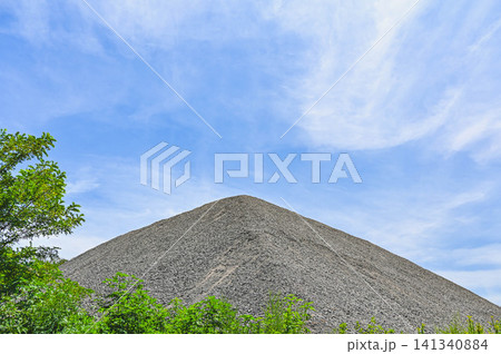 青空を背景にうず高く積まれた砂利の山 青空を背景にうず高く積まれた砂利の山 141340884