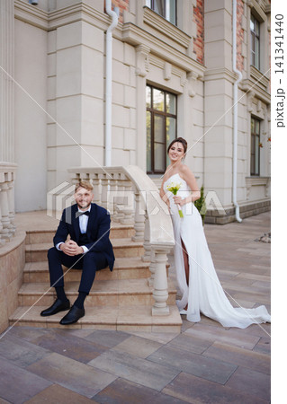A bride and groom in love and happy on the steps at the entrance to a building. 141341440
