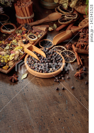 Rustic arrangement of juniper berries, dried citrus, cinnamon and aromatic herbs on a wooden table. 141341528
