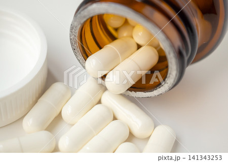 medicine pills capsule spilling out of bottle on white background medicine pills capsule spilling out of bottle on white background 141343253