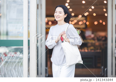スーパーで買い物を終え笑顔で店を出てくる女性 スーパーで買い物を終え笑顔で店を出てくる女性 141343844