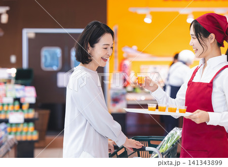 スーパーの店頭でスタッフから笑顔で試飲を受け取る女性 スーパーの店頭でスタッフから笑顔で試飲を受け取る女性 141343899