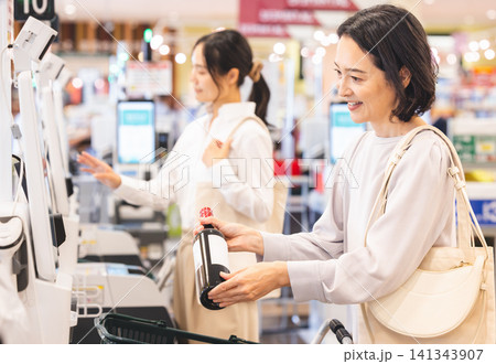 セルフレジで商品のバーコードを読み取る笑顔の女性客 セルフレジで商品のバーコードを読み取る笑顔の女性客 141343907