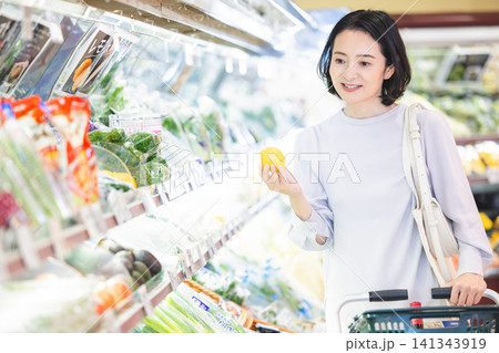 野菜売り場でレモンを手に取る50代の上品な女性 野菜売り場でレモンを手に取る50代の上品な女性 141343919