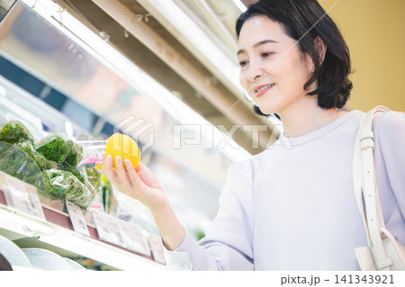 スーパーマーケットの野菜売り場でレモンを吟味する50代女性のアップ 141343921
