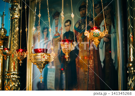 Golden Orthodox icon lamps hanging before an icon of Tsar Nicholas II's family. Golden Orthodox icon lamps hanging before an icon of Tsar Nicholas II's family. 141345268