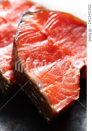 Closeup smoked sockeye salmon steak with glossy red flesh, textured skin, and rich moisture on dark surface with dramatic studio lighting and appetizing culinary detail Closeup smoked sockeye salmon steak with glossy red flesh, textured skin, and rich moisture on dark surface with dramatic studio lighting and appetizing culinary detail 141345303