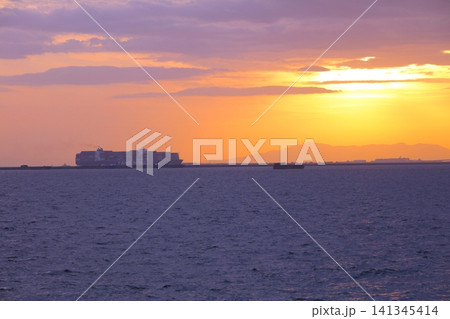 神戸港沖合を航行するコンテナ貨物船と夕陽(鳴尾浜臨海公園海づり広場より展望) 神戸港沖合を航行するコンテナ貨物船と夕陽(鳴尾浜臨海公園海づり広場より展望) 141345414