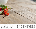 Close-up red currants with leaves arranged on rustic wooden table, glossy berries in soft daylight, shallow focus, natural texture, fresh harvest mood, warm countryside still life 141345683