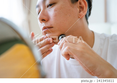 電動シェーバーで顎のひげを剃る40代男性の顔のアップ 電動シェーバーで顎のひげを剃る40代男性の顔のアップ 141345811