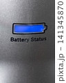 Blue battery indicator illuminated on textured metallic panel with partial status, closeup view showing recessed display, reflective grain, and subtle industrial detailing 141345870