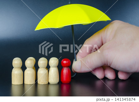 Hand placing a leader figure under umbrella representing motivation, support, and protective leadership. Hand placing a leader figure under umbrella representing motivation, support, and protective leadership. 141345874