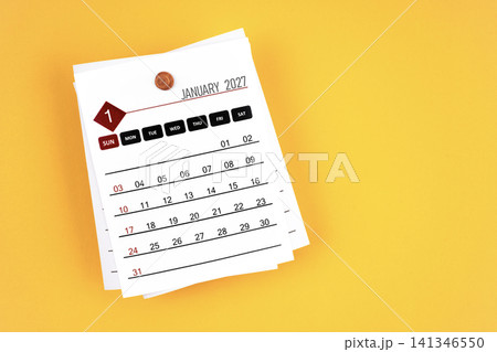 January 2027 calendar page with wooden push pin on yellow background. January 2027 calendar page with wooden push pin on yellow background. 141346550