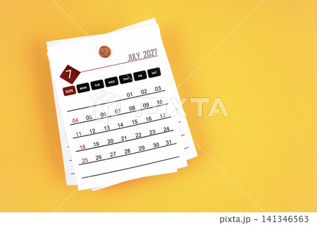 July 2027 calendar page with wooden push pin on yellow background. July 2027 calendar page with wooden push pin on yellow background. 141346563