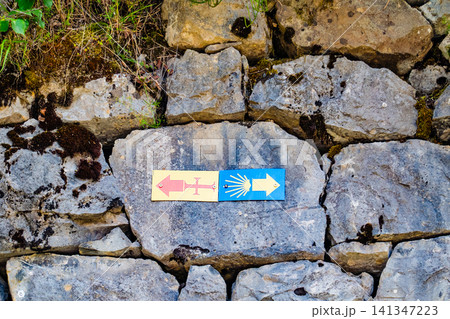 Camino de Santiago symbols and directional arrows on a stone wall Camino de Santiago symbols and directional arrows on a stone wall 141347223