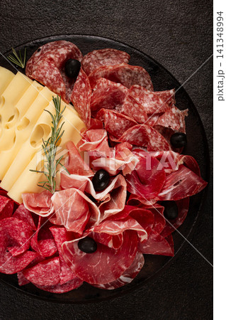 Cold cuts, appetizer, prosciutto, salami and ham, with maasdam cheese and olives, on a round plate, breakfast, top view, close-up, deserted Cold cuts, appetizer, prosciutto, salami and ham, with maasdam cheese and olives, on a round plate, breakfast, top view, close-up, deserted 141348994