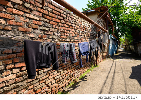 Clothes drying on a line by a brick wall 141350117