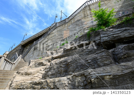 Stone wall and rocky cliff with stairs and blue sky 141350123