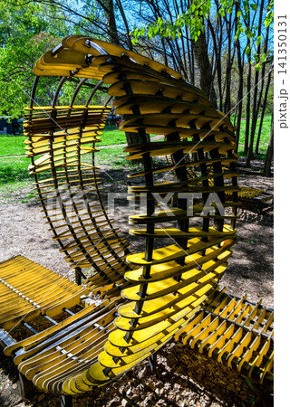 Yellow curved bench sculpture in a park 141350131