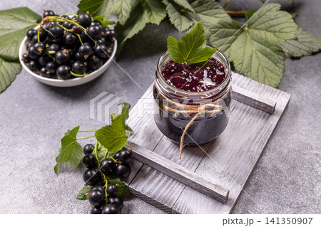Blackcurrant jam in jar with fresh berries and leaves Blackcurrant jam in jar with fresh berries and leaves 141350907