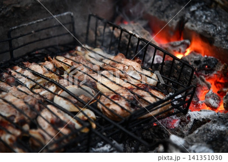 Unrecognizable man cooking seafood on a barbecue grill in the backyard. Unrecognizable man cooking seafood on a barbecue grill in the backyard. 141351030