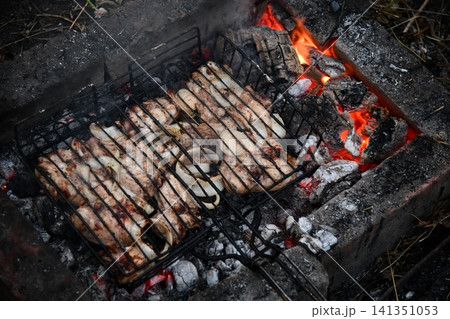 Unrecognizable man cooking seafood on a barbecue grill in the backyard. Unrecognizable man cooking seafood on a barbecue grill in the backyard. 141351053