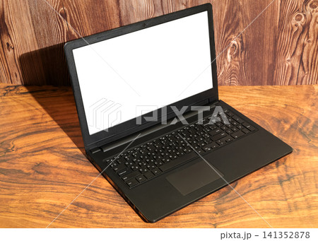 open laptop with a white screen stands on a wooden table surface at an angle 141352878