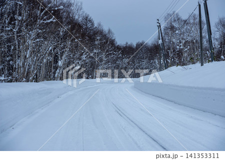 雪道を進む冬の山道、雪に覆われた樹林に囲まれた風景 雪道を進む冬の山道、雪に覆われた樹林に囲まれた風景 141353311