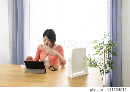 自宅でオンラインメイクレッスンを受ける若い女性 141354013
