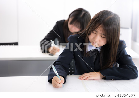 綺麗な新緑背景の教室で真剣にテストに取り組む日本人女子高校生複数 受験、定期テストや英検の模試の学生 綺麗な新緑背景の教室で真剣にテストに取り組む日本人女子高校生複数 受験、定期テストや英検の模試の学生 141354377