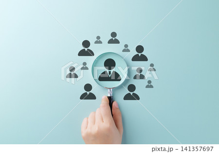 Talent Search and Recruitment Concept. Hand holding magnifying glass over candidate icons, symbolizing talent acquisition, recruitment, and employee selection process. HR, Human resources, CV Profile, 141357697