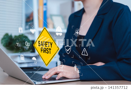 Workplace Safety and Risk Prevention Concept. A professional works on laptop with safety icons and SAFETY FIRST sign, representing occupational safety, risk prevention, and workplace hazard awareness. Workplace Safety and Risk Prevention Concept. A professional works on laptop with safety icons and SAFETY FIRST sign, representing occupational safety, risk prevention, and workplace hazard awareness. 141357712