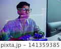 Futuristic young Asian software developer with glasses coding with virtual hologram screens in neon light. Cyber security expert, hacker or programmer working on AI technology project. 141359385