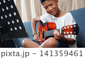 Happy Asian boy playing acoustic guitar and practicing music lesson at home. 141359461