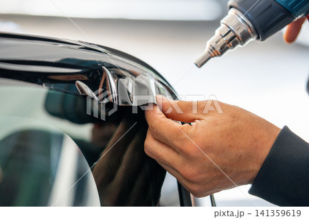 A car wrapping specialist applies a polyurethane film to the car. Detailer PPF 141359619